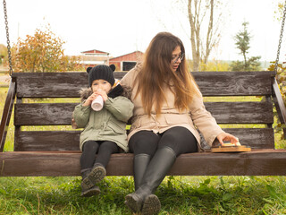 mother and child have a snack on a bench