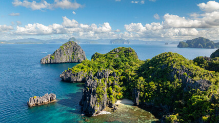 Islets and beach in Miniloc Island. Blue sky and clouds. El Nido, Philippines.