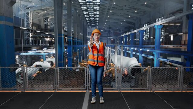 Full Body Of Asian Female Engineer With Safety Helmet Disapproving With No Hand Sign While Standing In Factory Manufacture Of Wind Turbines 