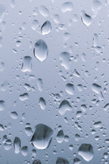 Raindrops on the window. Water falling on the glass. natural background, freshness. Cold rainy weather. Close-up.