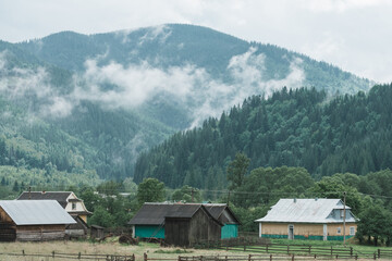 Fototapeta premium Cloudy mountain village after the rain. Fog on the mountain after the rain