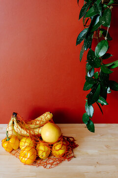 Yellow vegetables and fruits in mesh bag at table, zero waste