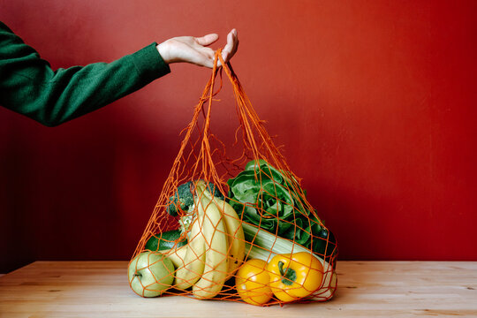 Person with mesh bag with various vegetables and fruits, zero waste