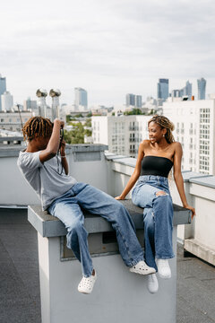 A man takes a picture of a woman on the roof