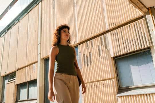 Confident young woman standing near modern building
