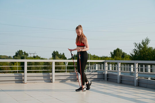 The athlete shakes her biceps with an expander