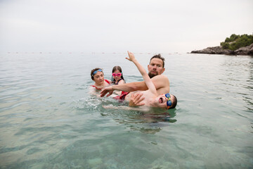 Man carries naughty son out of the water