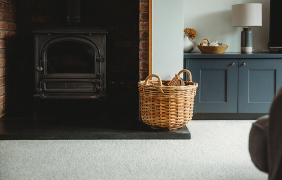 Basket of logs in front of a fireplace.