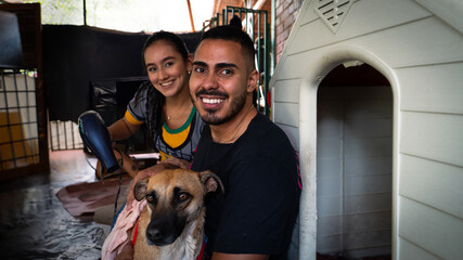 2 Colombian friends looking at the camera with a dog