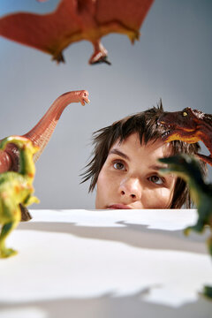 young woman looks at dinosaurs from under the table