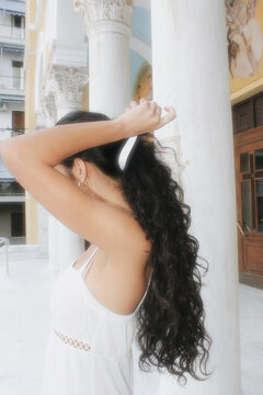Girl in White Dress Tying Hair Ribbon in Athens Greece