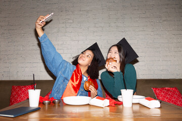 Happy young girlfriends taking selfie after graduation