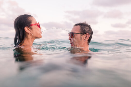 Hilarious couple spitting sea water to each other