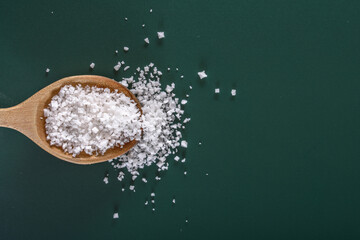 Natural Seasoning: 4K Ultra HD Image of White Salt in Wooden Spoon on Green Background