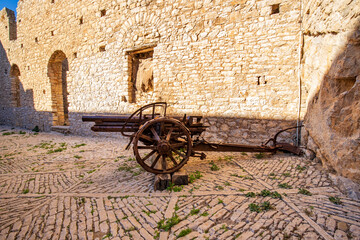 Old cannon over stone wall. Old castle. Ancient cannon on wheels.