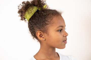 A young African American girl in profile with a green bow in her hair, used for beautiful young...