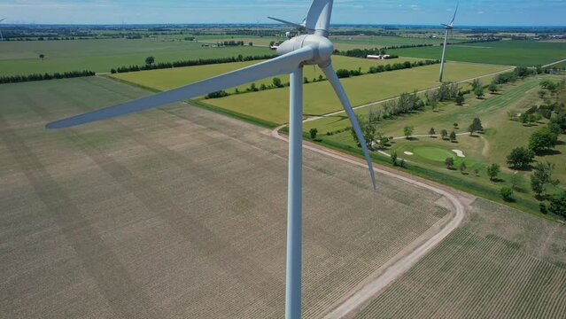 Canadian hydro wind turbine with blades spin. Windmills on the food farm generating green energy. Sustainable alternative energy. Blue sky panorama. Energy shortage, prices and crisis concept.