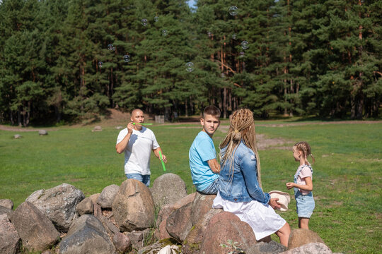A family enjoys an outdoor adventure in a pine forest clearing, This picture encapsulates the spirit of childhood play and family escapades in nature.