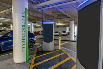 Electric vehicle charging station at parking structure has one car charging and one open stall for...