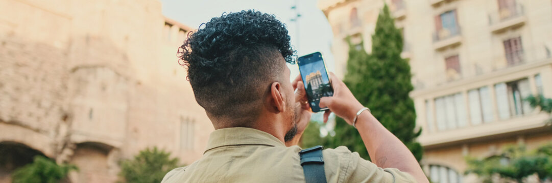 Close up, young man dressed in an olive-colored shirt takes photo on the street of the old city, Back view, Panorama