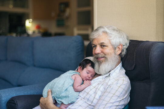 Newborn taking a nap with her grandfather