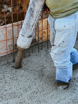 Construction worker holding pipe of pump machine while concreting ceil