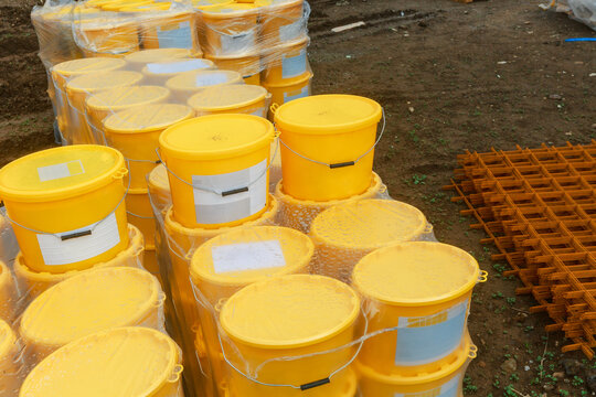 Yellow paint buckets stacked on a construction site.