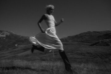 Artistic black and white photo of a model running in mountains