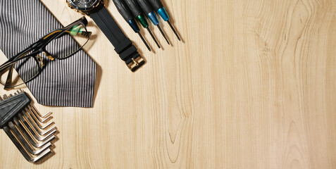 Work tools, watch, glasses, planner, and tie neatly arranged on a wooden surface. Father’s Day...