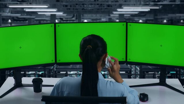 Back View Of Asian Woman Talking On Mobile Phone While Working With Mock Up Multiple Computer Monitor In Data Center