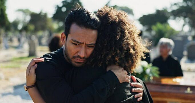 Funeral, man and woman hug at graveyard for memorial service at burial with empathy, support and comfort. Death, grief and people embrace at cemetery with sympathy, care and cry together at coffin.
