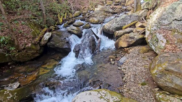 footage of the rushing waters of Smith Creek with rocks and lush green trees and plants at Anna Ruby Falls in Helen Georgia USA