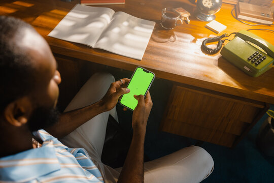 A man with a green-screen phone in the office