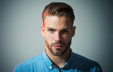 Closeup portrait of serious fashionable bearded man in denim shirt. Sexy handsome male model with...