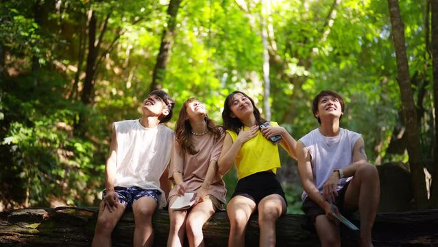 Group of Young Asian man and woman enjoy and fun outdoor lifestyle travel nature forest on summer holiday vacation. Happy generation z people friends relaxing and playing together at waterfall lagoon.