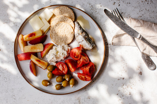 A snack plate of fruit, cheese, sardines and oat cakes.