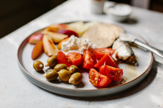 Tomatoes and other small bits on a plate in dappled light. 