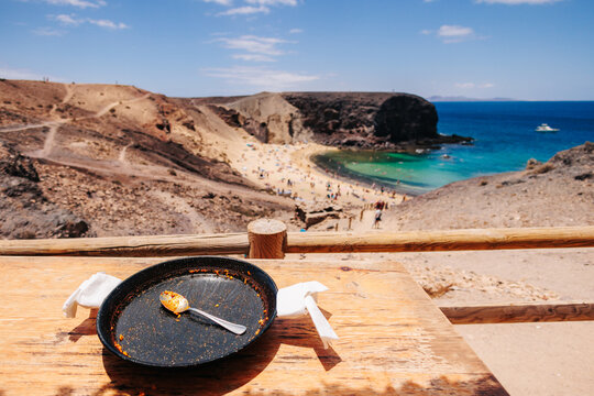 ugc pov view, empty paella meal pan with amazing beach in background 