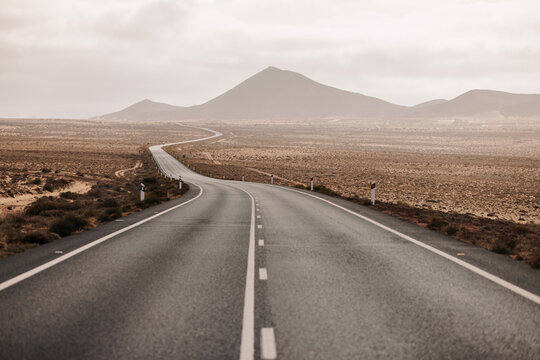 Empty lonely road in desert with sunny and cloudy sky