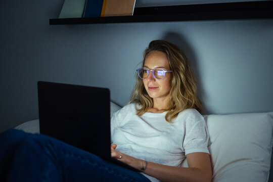 Smiling Young Woman Typing on Laptop at Night