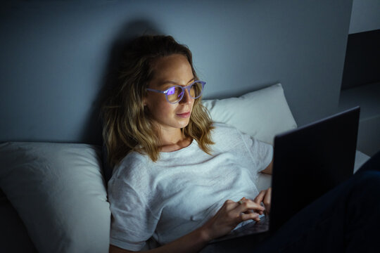 Young Woman Typing on Laptop at Night