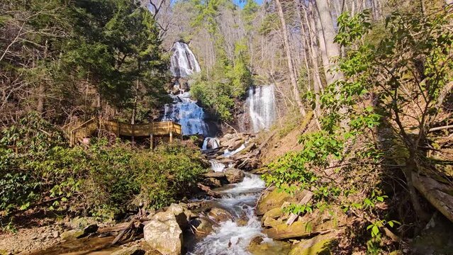 tilt footage of the rushing waters of Smith Creek and waterfall at Anna Ruby Falls with rocks and lush green trees and plants in Helen Georgia USA