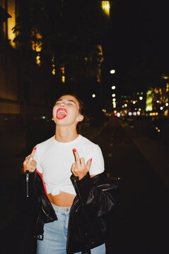 Young woman shows a sign "fuck you" and shows the tongue 