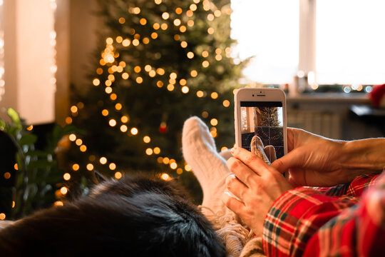 Woman take phone photo of festive Christmas tree at home