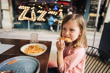 Little girl eating pizza in a cafe