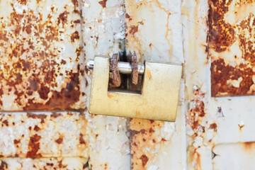 Closed metal fence. Padlock background. Abandoned property. Gate closed with massive lock. Private property forbidden entry. Padlock hanging on rusty door.