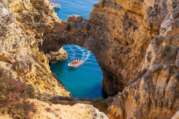 Tourists on motor boat at the cathedral arch at Ponta da Piedade, Algarve coast, Lagos, Portugal.