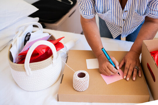 Woman Customizing Gift Package with Handwritten Card 