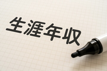 生涯年収と書かれたノートとマーカー