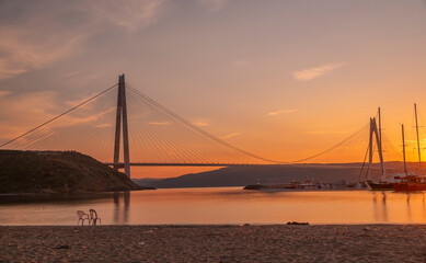 istanbul yavuz sultan selim bridge taken from the beach towards sunset people dogs with blue sea and sky and evening lighting